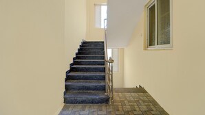 A staircase with a metal handrail, a window with blinds, and a tiled floor.