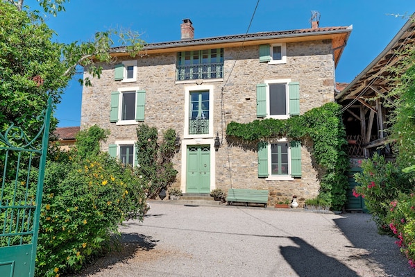 A stone building with a green door, multiple windows, and a balcony.
