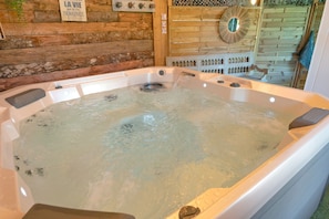 A hot tub with a wooden wall backdrop, a sign, and a mirror.
