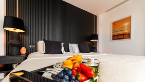 A hotel room with a bed, bedside lamps, a tray with fruit, and a painting on the wall. - Modern Luxury Villa with Panoramic  View (Marbella)