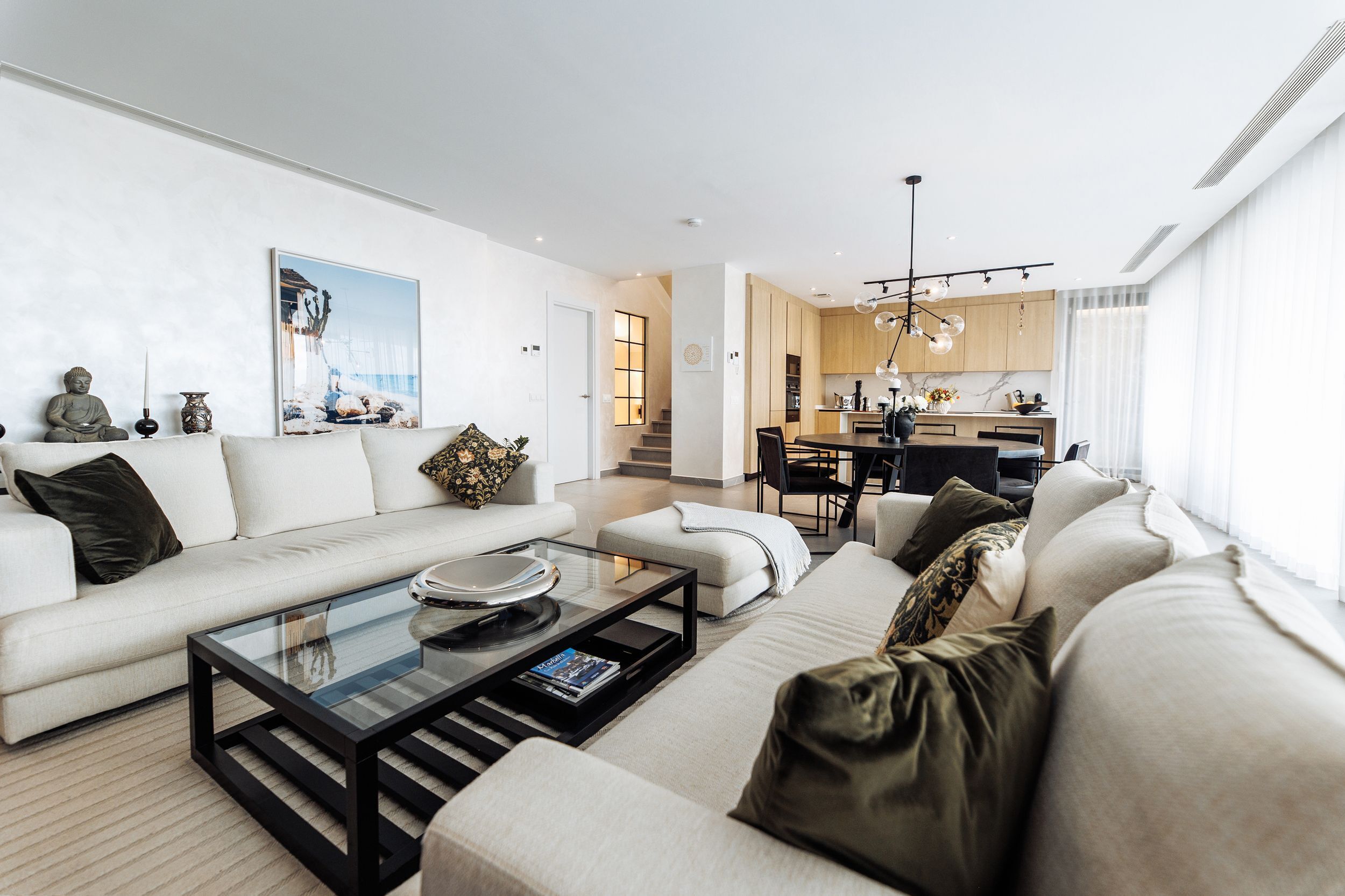 A modern living room with a sofa, coffee table, and a view into the kitchen.