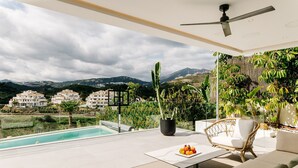 A modern outdoor living area with a pool, seating, and a view of buildings and hills. - Modern Luxury Villa with Panoramic  View (Marbella)