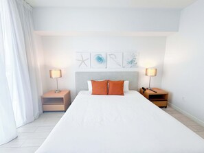 A hotel room with a large bed, two bedside tables, and a headboard with artwork. - High-Floor Intracoastal View Apt - Beach Access (Hallandale Beach)