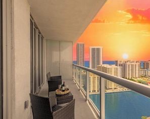A balcony with wicker chairs, a table, and a bottle of wine. - High-Floor Intracoastal View Apt - Beach Access (Hallandale Beach)