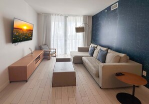 A modern living room with a sofa, a coffee table, a TV, and a map on the wall. - Top-Floor Waterway 2BR · Beachwalk Resort FL (Hallandale Beach)