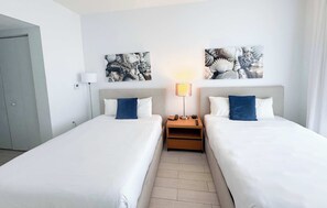 A hotel room with two beds, a nightstand with a lamp, and artwork on the wall. - Top-Floor Waterway 2BR · Beachwalk Resort FL (Hallandale Beach)