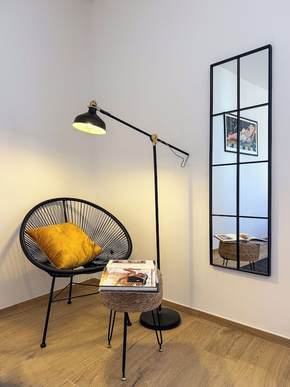 A room with a black floor lamp, a black chair with a yellow cushion, a small round table with a woven basket, and a large mirror on the wall. - Elegant & Spacious 3BR with Terrace in city center ✺ WI-FI ✺ AC ✺ (Firenze)