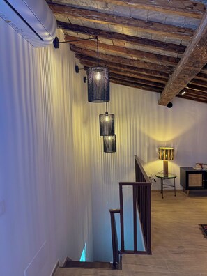 A staircase with a wooden handrail, a wall with vertical blinds, and a hanging light fixture. - Elegant & Spacious 3BR with Terrace in city center ✺ WI-FI ✺ AC ✺ (Firenze)