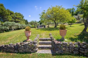 A stone staircase leading up to a grassy area with two large terracotta pots and a stone wall.