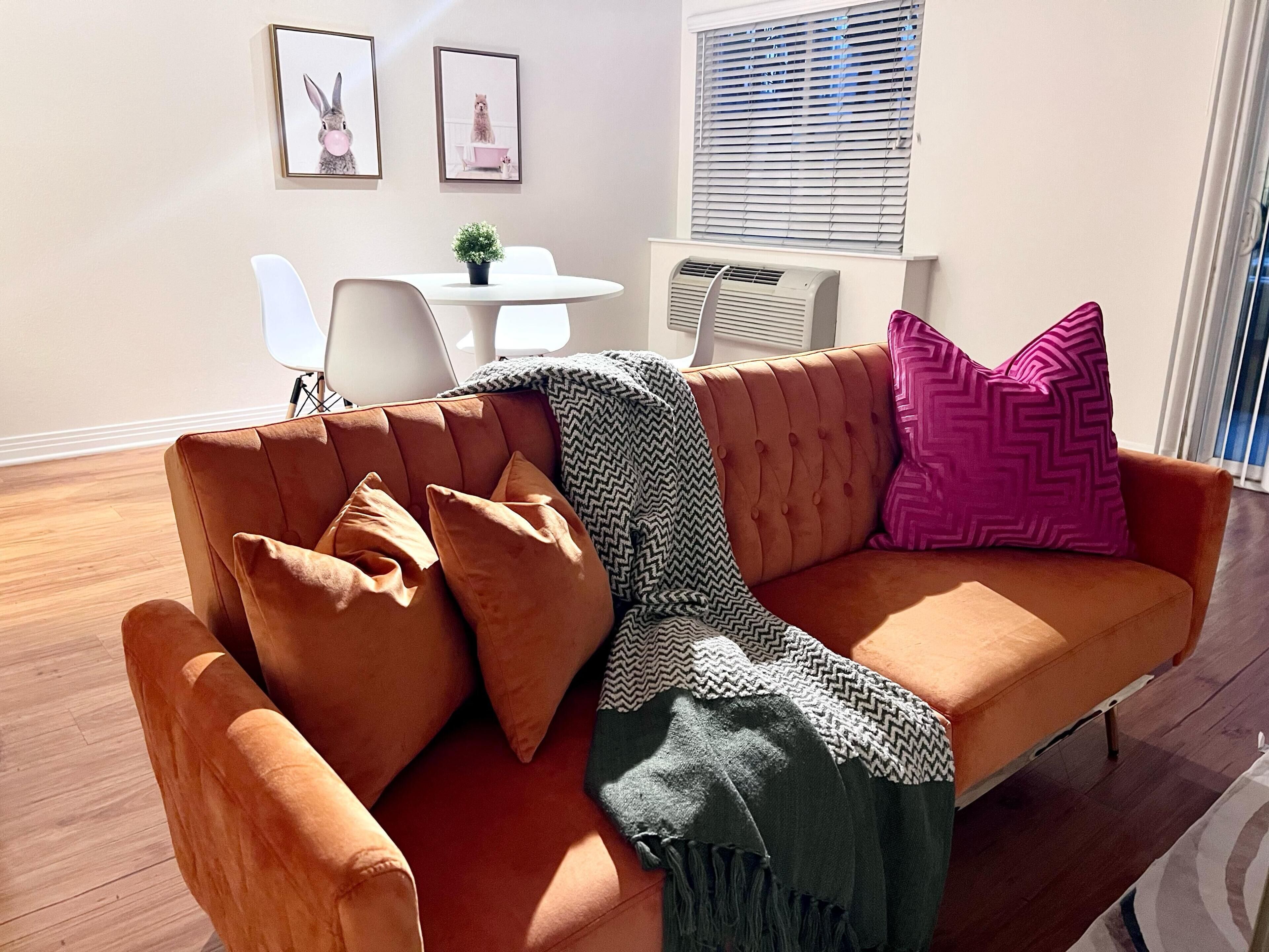 Ein Wohnzimmer mit einem braunen Sofa, einem kleinen Tisch und zwei gerahmten Bildern an der Wand.
