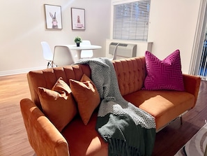 Ein Wohnzimmer mit einem braunen Sofa, einem kleinen Tisch und zwei gerahmten Bildern an der Wand.