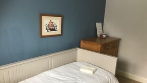 A bedroom with a single bed, a dresser, and a framed picture on the wall. - House Sleeps 9 With Indoor Pool (Chichester)