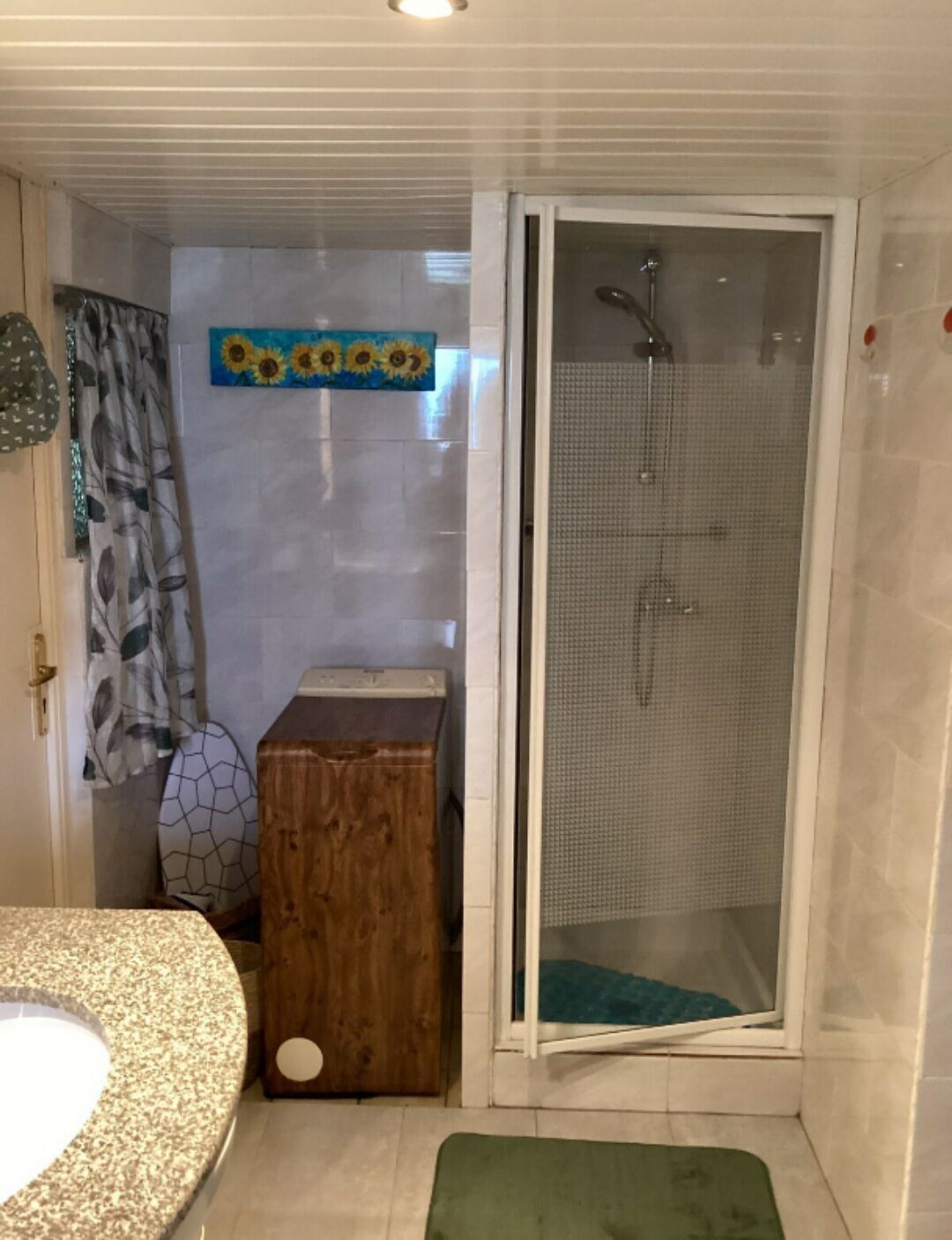 Un baño con ducha, lavamanos, un armario de madera y un perchero para toallas.