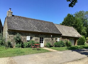 A stone house with a sloped roof, a front door, and a small porch area.