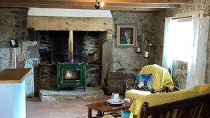 Een rustiek interieur met een stenen openhaard, houten meubels en een betegelde vloer.