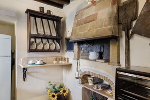 A kitchen with a built-in oven, shelves with dishes, and a flower arrangement. - Apartment 'Podere Del Botruccio - Girasole' with Shared Pool, Garden & Wi-Fi (Pomarance)
