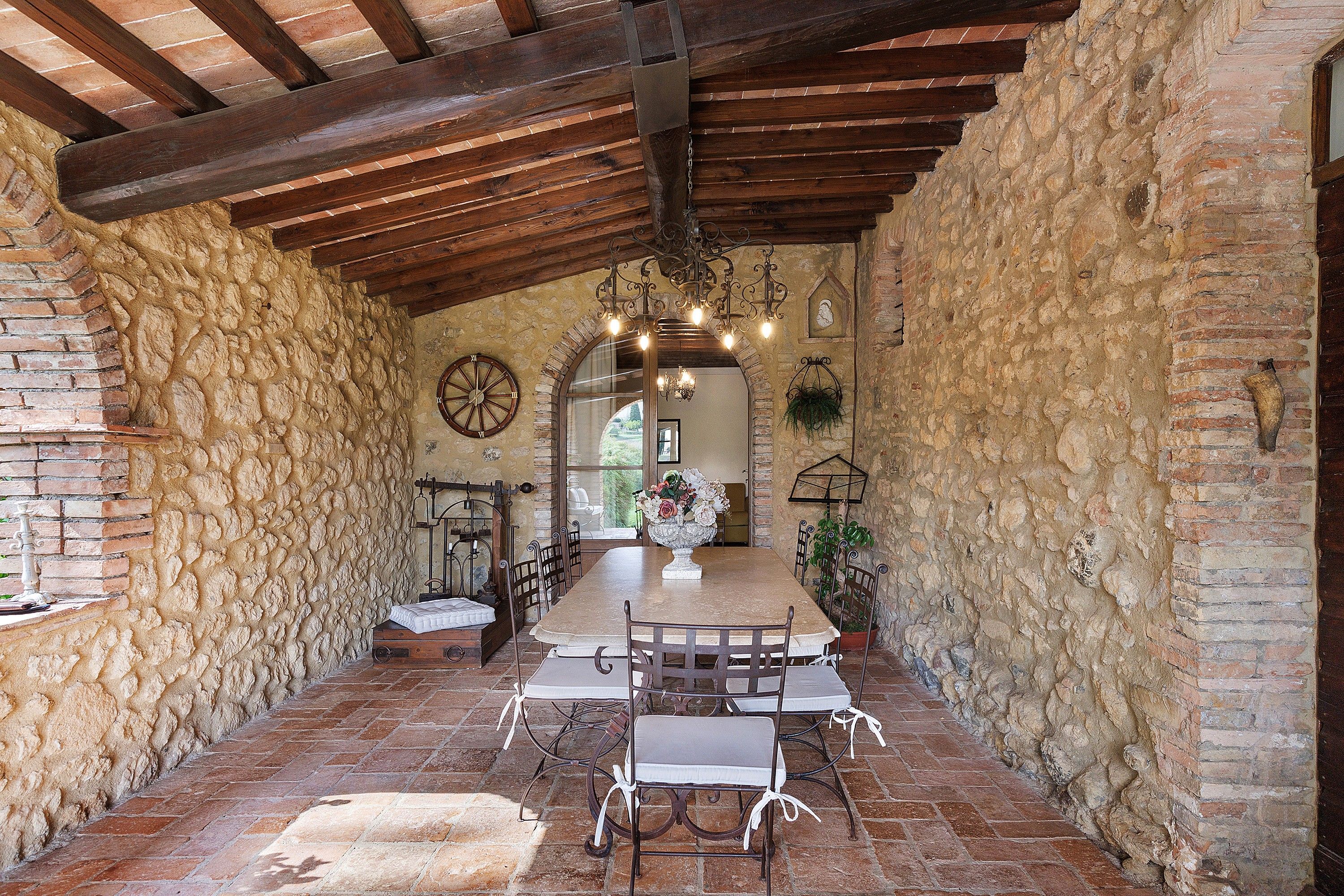 Un coin repas rustique avec une longue table, des chaises et un lustre.