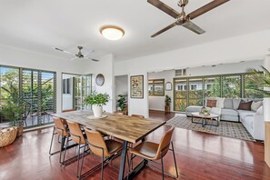 A spacious living area with a dining table, chairs, a sofa, and a ceiling fan.