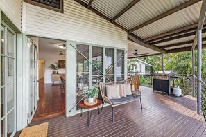 An open-plan living area with a dining space, a grill station, and a view of the garden. - Tropica Lookout A Serene Coastal Pool House (Rapid Creek)