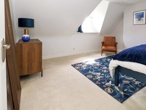 Ein Schlafzimmer mit einem Bett, einem Sessel, einem Holzschrank, einem Fenster und einer Tür.