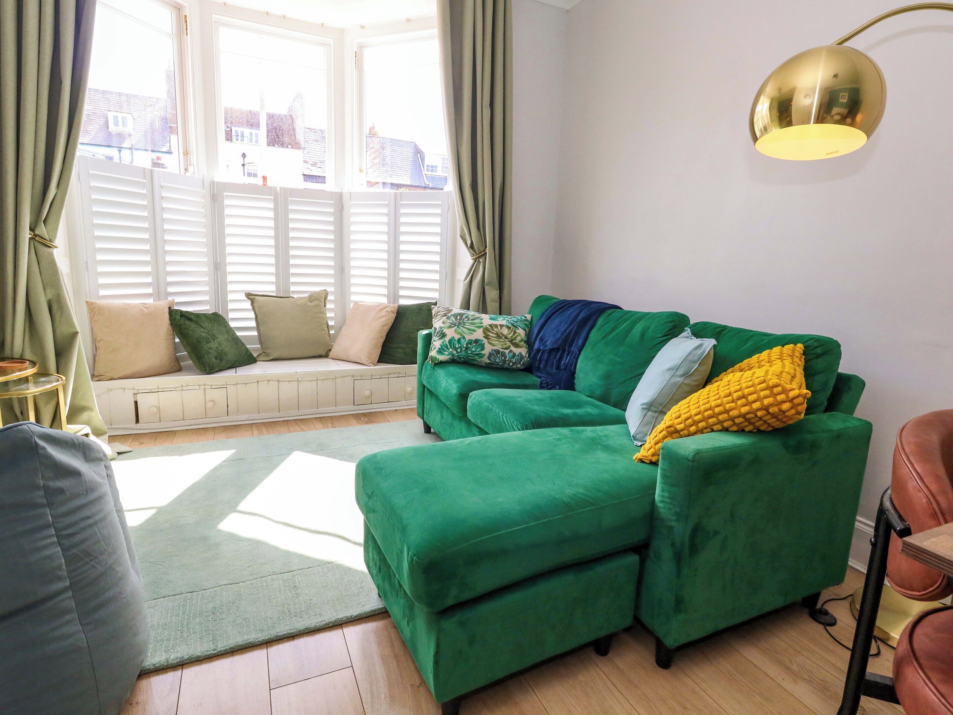 A green sofa with a bench, a round table, and a lamp.