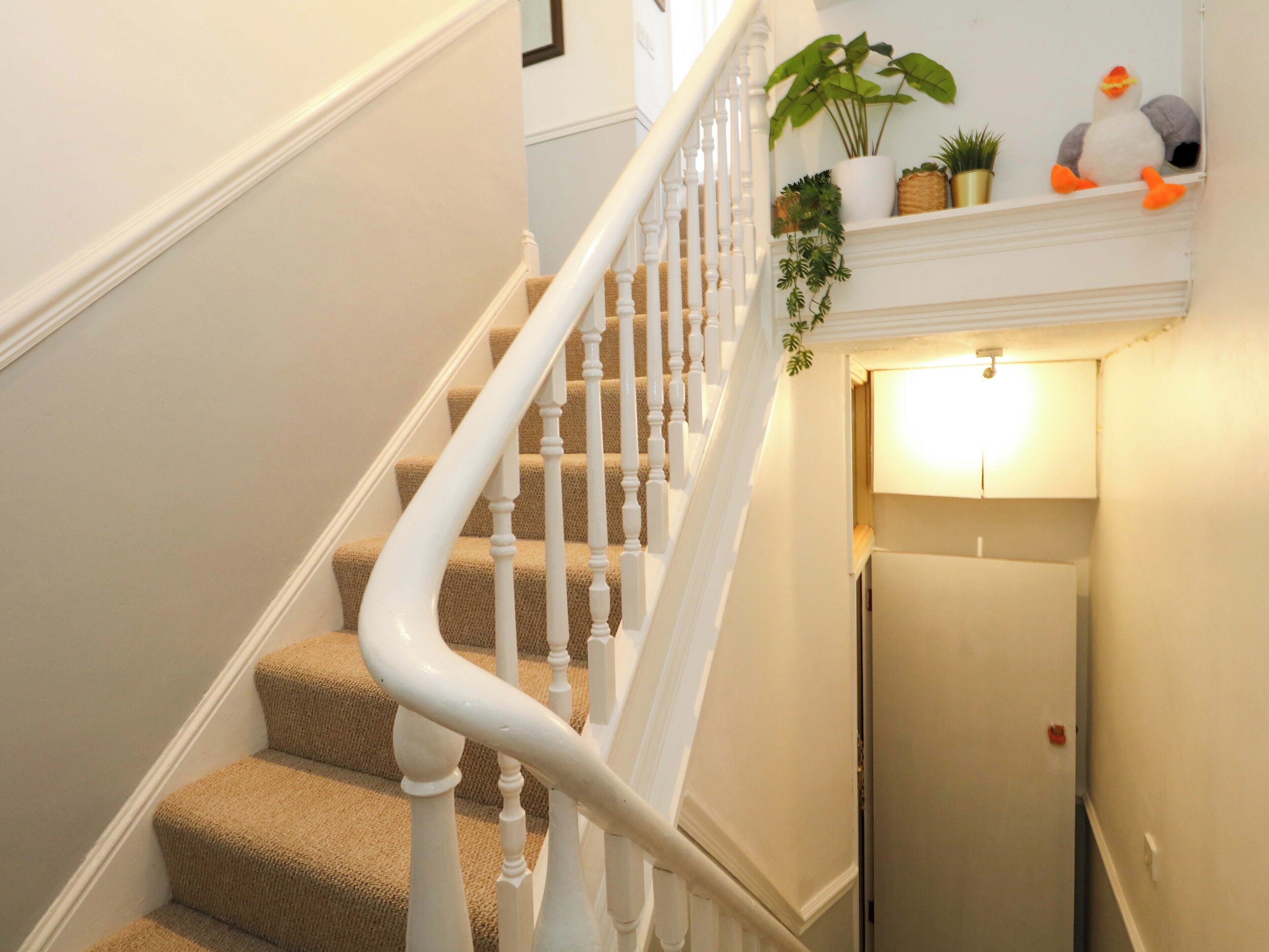 A staircase with white balusters and beige carpeted steps leading to a landing.