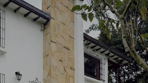 A building with a stone column, white walls, and a balcony with metal railings. - Sereno Hostels (Bogota)