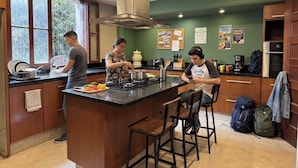 A modern kitchen with a central island, wooden cabinets, and a stainless steel range hood. - Sereno Hostels (Bogota)