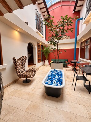 A spacious indoor area with a pool table, a chair, and a potted plant. - Sereno Hostels (Bogota)