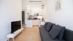 Ein modernes Wohnzimmer mit Flachbildfernseher, grauem Sofa und einem kleinen Beistelltisch.
