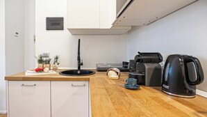 Eine moderne Küche mit Spüle, einer Kaffeemaschine und einer Brokasten.