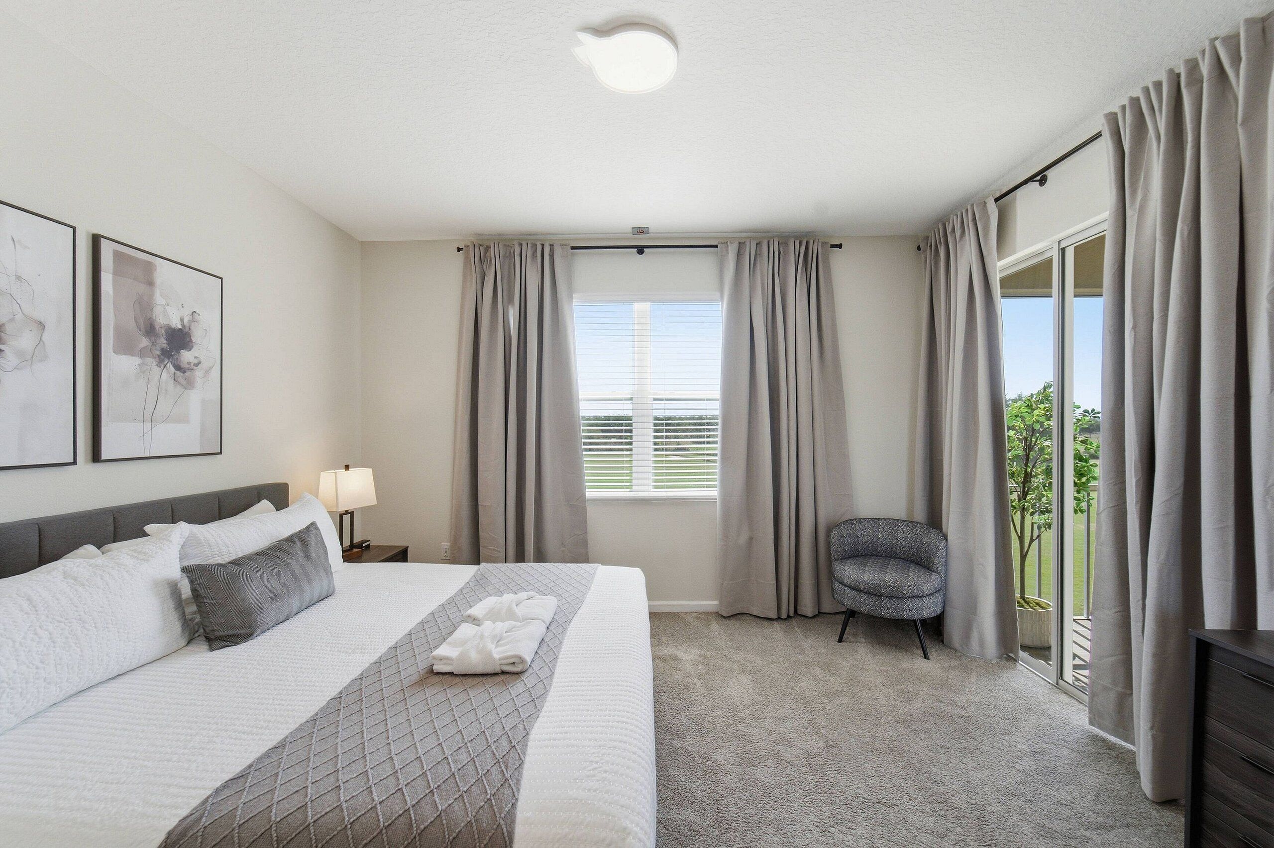 Een hotelkamer met een bed, een stoel, een raam met gordijnen en een balkon.