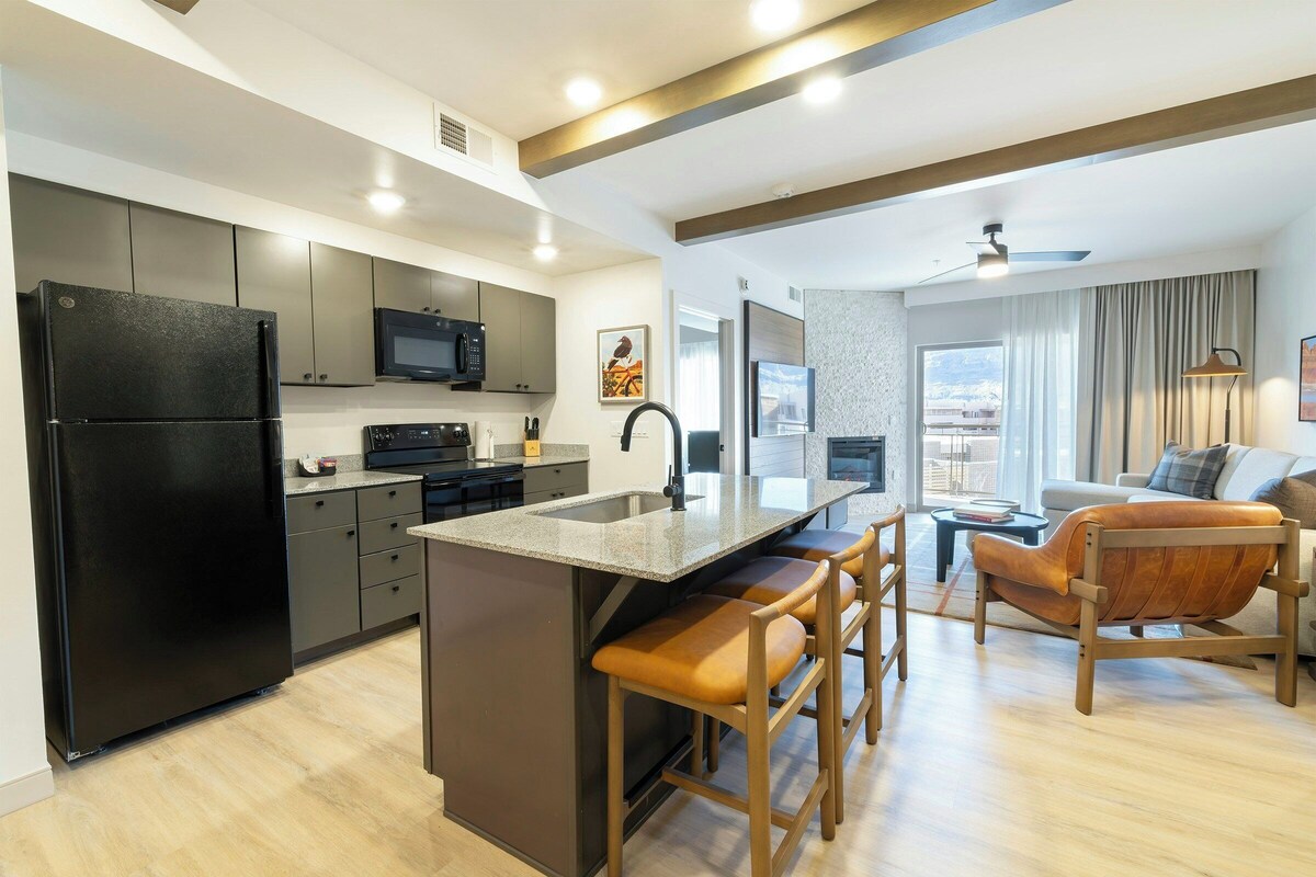 A modern kitchen with a central island, a dining area with a sofa and chairs, and a view of the city.