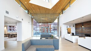 A modern lobby with a large seating area, a reception desk, and a view of the outside.