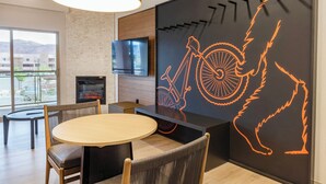 A modern interior with a round dining table, chairs, a flat-screen TV, a fireplace, and a wall with a bicycle and abstract art.