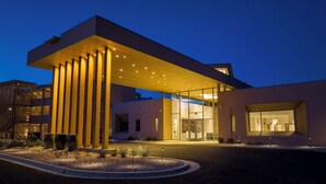 A modern building with a prominent overhang, large glass entrance, and a well-lit facade.