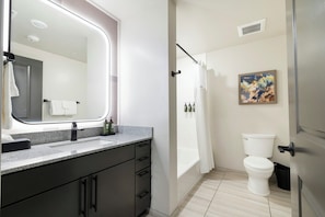 A bathroom with a sink, mirror, toilet, and shower curtain. - EBAC Moab (Moab)