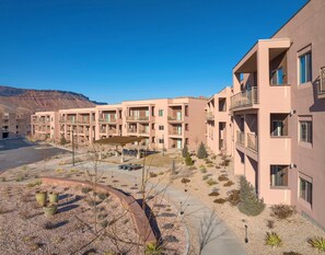 A multi-story residential building with balconies, a covered outdoor seating area, and a landscaped courtyard with desert plants. - EBAC Moab (Moab)