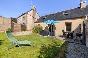 A backyard with a lawn, a lounge chair, a table with chairs, a barbecue grill, and a blue umbrella. - Holiday Home 'Gîte Aber 3km Plages' with Private Terrace, Garden & Wi-Fi (Telgruc-sur-Mer)