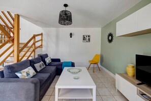 A modern living room with a sofa, coffee table, TV, and a staircase. - Holiday Home 'Gîte Aber 3km Plages' with Private Terrace, Garden & Wi-Fi (Telgruc-sur-Mer)