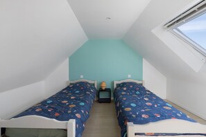 A small, narrow room with two beds, a nightstand with a lamp, and a window. - Holiday Home 'Gîte Aber 3km Plages' with Private Terrace, Garden & Wi-Fi (Telgruc-sur-Mer)