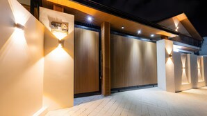 Un bâtiment moderne doté d’une façade en bois, d’une entrée illuminée et d’un balcon.