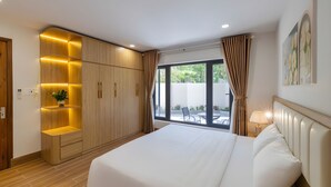Une chambre d’hôtel avec un grand lit, une armoire en bois dotée d’étagères éclairées, une fenêtre avec des rideaux et une vue sur l’extérieur.