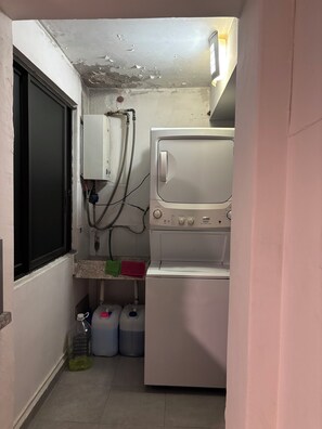 A laundry room with a washing machine, a water heater, and storage tanks. - Spacious and centrally located apartment 6 stations from downtown Mexico City and 8 from Banorte stadium. (Cdmx)