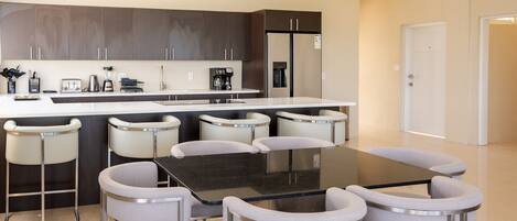 Une cuisine moderne avec des meubles de couleur sombre, un îlot central et des tabourets de bar.