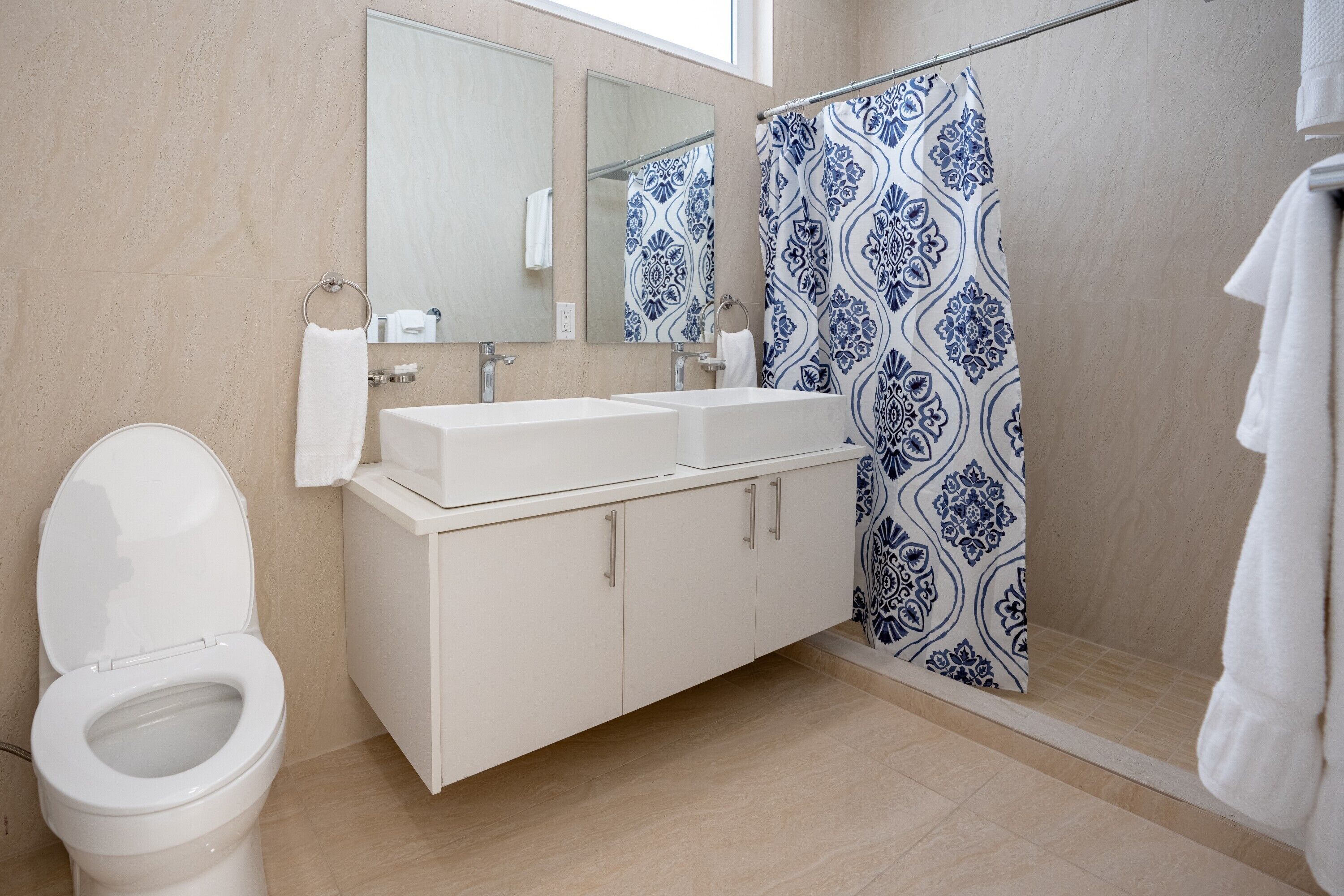 A bathroom with a toilet, a sink, a mirror, and a shower curtain.