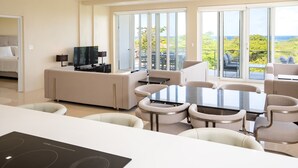 A modern hotel room with a dining area, a TV, and a balcony with a view. - Belmont Villas (Vaughans)