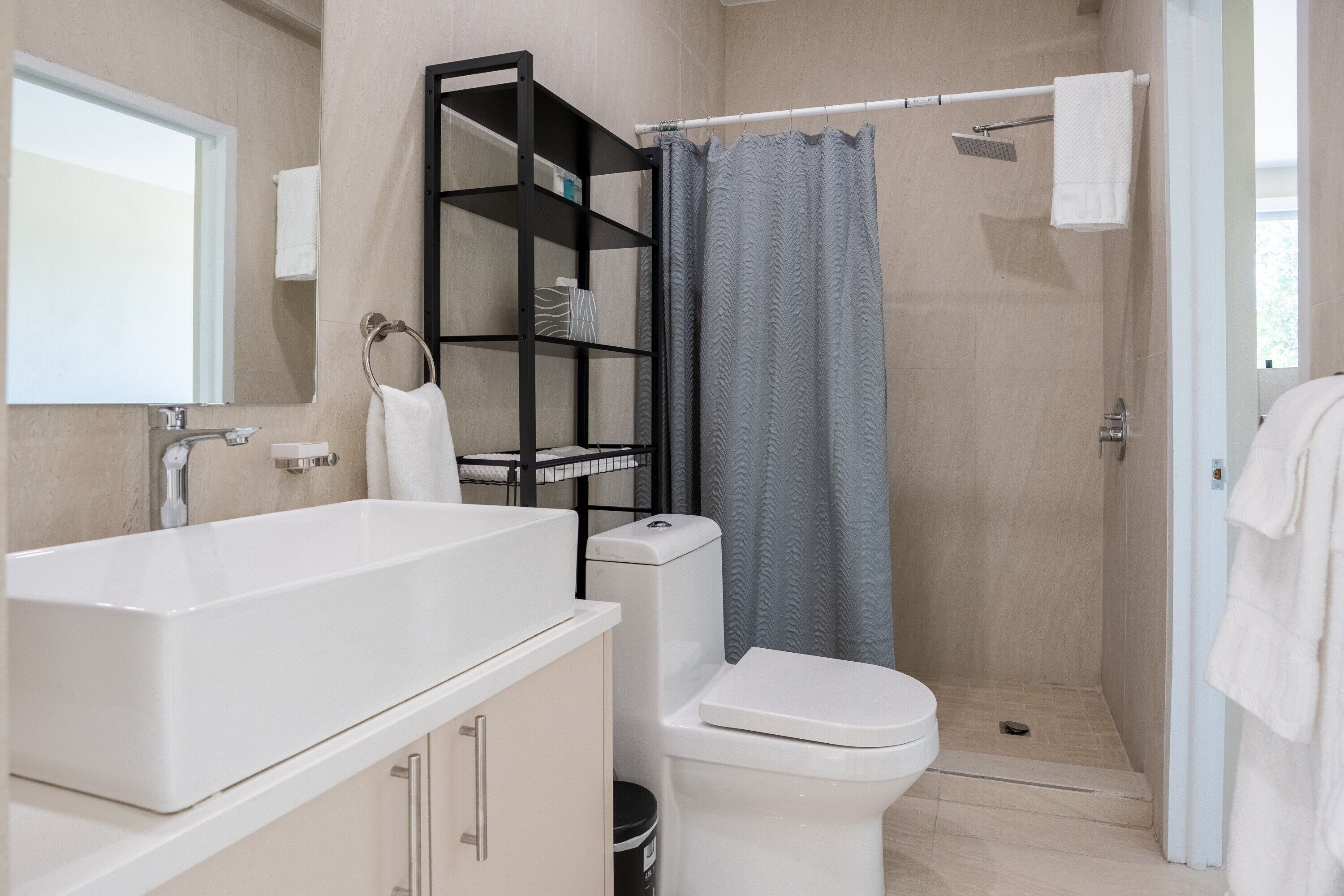 A bathroom with a white sink, toilet, and shower curtain.