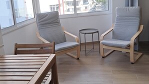 Un balcón con dos sillas, una mesita y vista a la ciudad.
