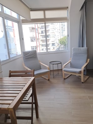 Ein Balkon mit zwei Stühlen, einem kleinen Tisch und Blick auf eine Stadtlandschaft.